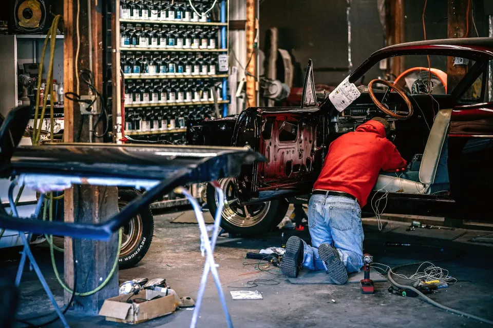 A mechanic restoring a classic car in a busy workshop