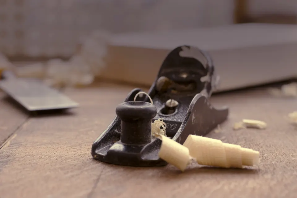 A wood plane with curled shavings on a workbench